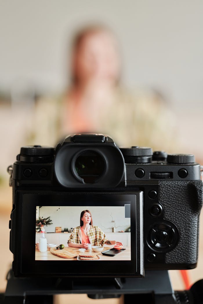A woman vlogs a cooking session in her kitchen, captured through a camera viewfinder.